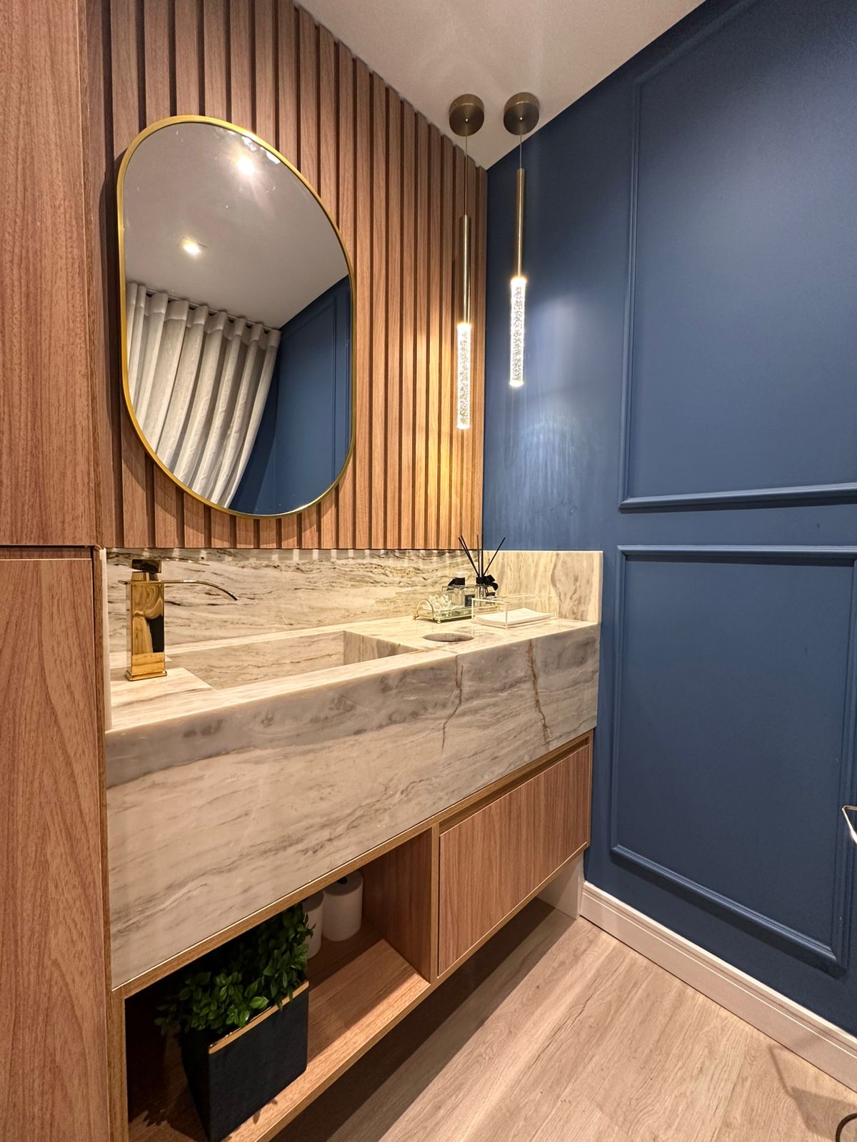 Lavabo sofisticado com bancada em mármore e espelho dourado
