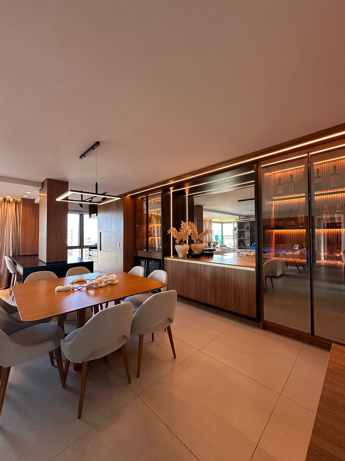 Sala de jantar com adega em madeira e iluminação LED