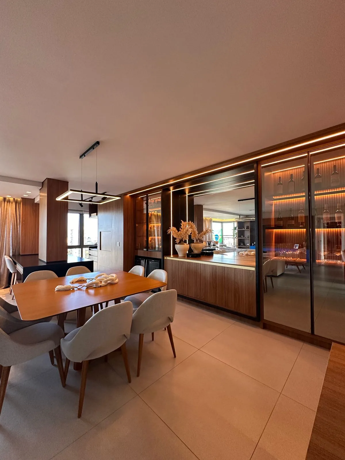Sala de jantar com adega em madeira e iluminação LED